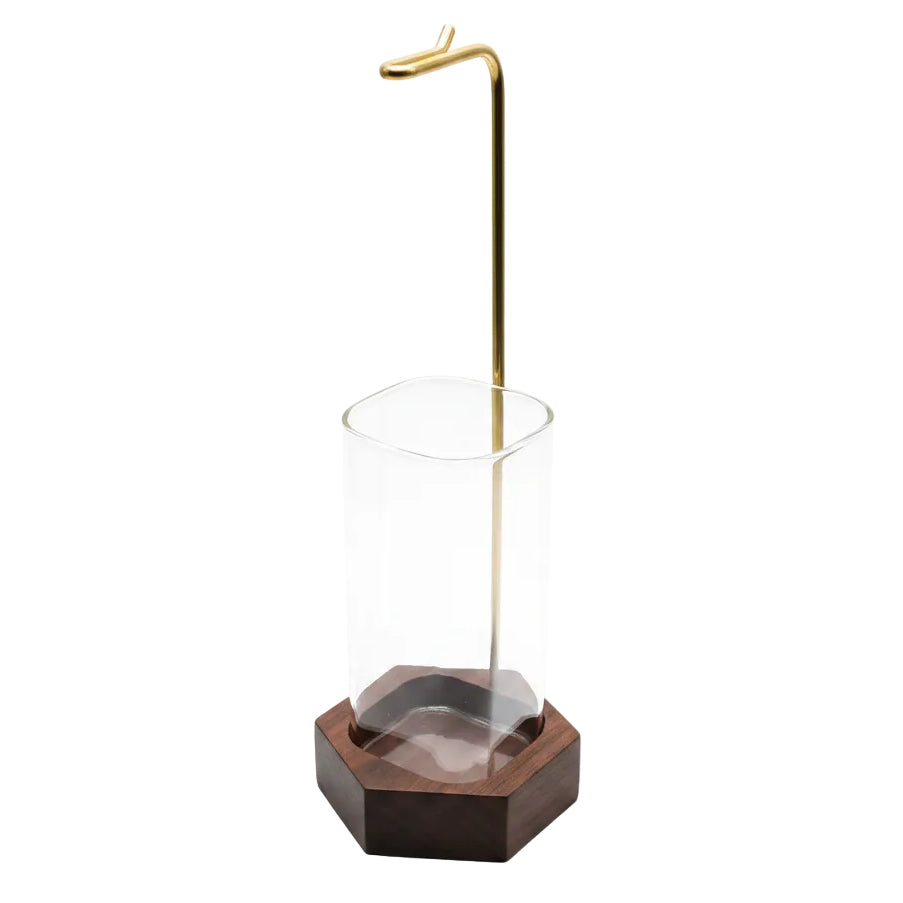 Glass with a wooden base and metal stand on a metallic surface